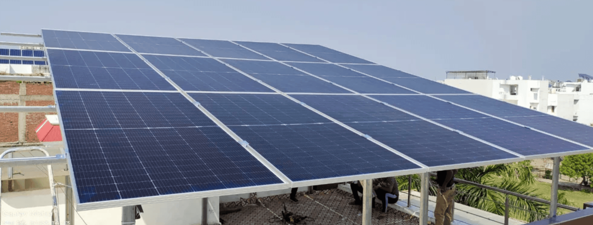 Large solar panels installed on a rooftop with buildings in the background.