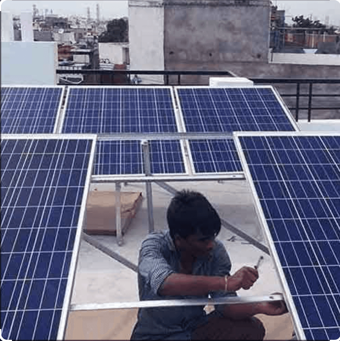 Person installing solar panels on a rooftop with a city skyline in the background.